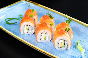Japanese traditional rolls with seafood and fish, vegetables, on a black background.