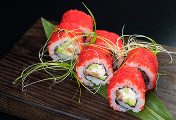 Japanese traditional rolls with seafood and fish, vegetables, on a black background.
