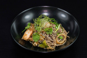 Asian noodles with vegetables and meat on a black background.