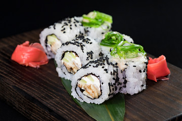 Japanese traditional rolls with seafood and fish, vegetables, on a black background.
