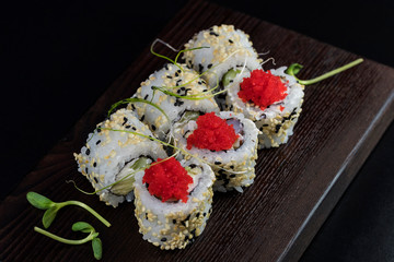 Japanese traditional rolls with seafood and fish, vegetables, on a black background.