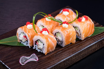 Japanese traditional rolls with seafood and fish, vegetables, on a black background.