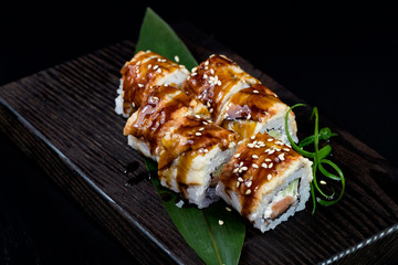 Japanese traditional rolls with seafood and fish, vegetables, on a black background.