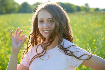 girl holds in her hand a white pill for allergies, being in a yellow flowering field