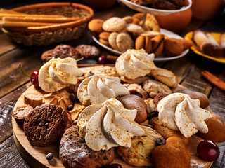 Oatmeal cookies and sand chocolate cake with cherry berry and crispy wafer rolls with cream on cutting board on wooden table in rustic style. Limitations for diabetics. Temptation for gourmet.