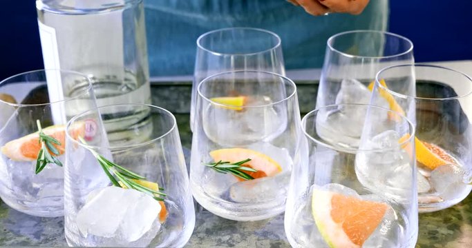 Woman hands garnishing cocktails with rosemary and grapefruit slices