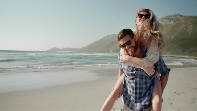 Loving couple having fun on beach piggy-back ride - Powered by Adobe