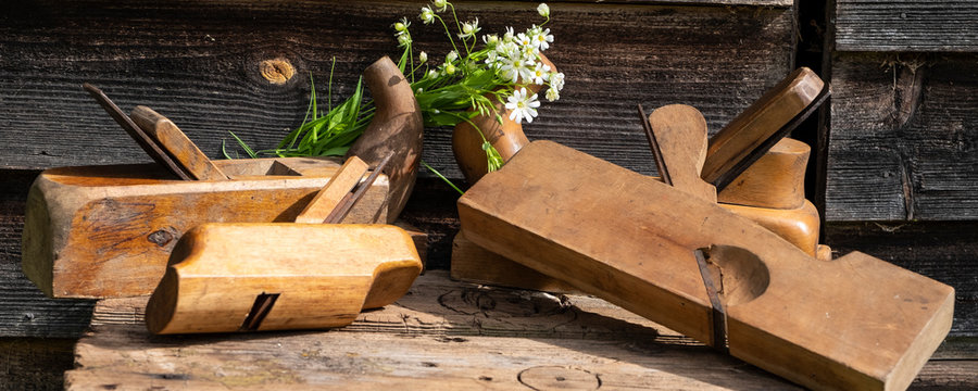 Antique hand tools, a group of planes. Wildflowers and carpentry tools. Panoramic photo.