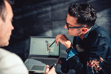 Data analyst pointing at report on laptop