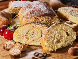 Sand nut chocolate cookies and rolled biscuit on board and cinnamon stick. Straw pastry with cup of coffee with dessert spoonon on wood kitchen table in rustic style. Supplement for breakfast.