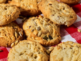 Oatmeal cookies with husk whole oats on red kitchen gingham checkered cotton fabric on table in farm-style.