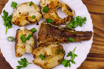 Roasted pollock in white plate on a wooden table