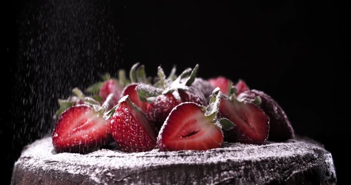 Dusting icing sugar over delicious chocolate cake with dark background