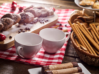 Oatmeal chocolate cookies with coffee grains and cherry, powdered sugar on kitchen cutting board with checkered fabric on wooden table in village style for picnic. Eat in small portions.
