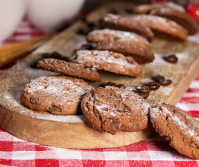Oatmeal cookies with husk oats and cherry cupcake with powdered sugar on kitchen cutting board gingham checkered cotton fabric on table in village style for picnic. Useful for digestion.