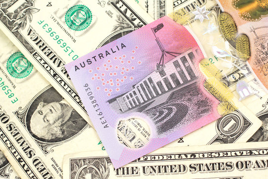 A close up image of an Australian five dollar bill with United States one dollar bills in macro