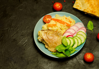 cous cous with chicken and vegetables and greens on a black background near Eastern pita bread, selective focus