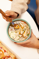 Young woman is having lunch in a cafe eating noodle soup and pizza with smoked salmon