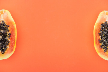 top view of ripe papaya halves with black seeds isolated on orange