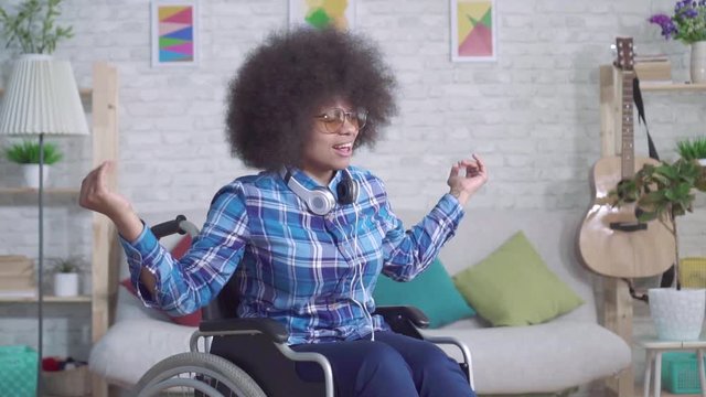 cheerful disabled african woman with an afro hairstyle dancing sitting in a wheelchair slow mo