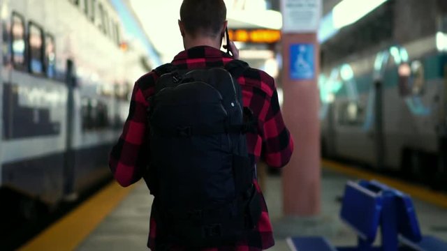 Slow motion: Beautiful young male walking on train platform at Los Angeles train station. Concept of travel active lifestyle, millennial urban life, summer vacation.