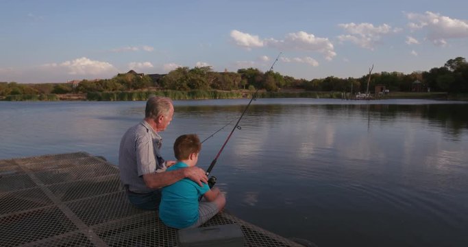 Grandfather and grandson fishing at a small lake