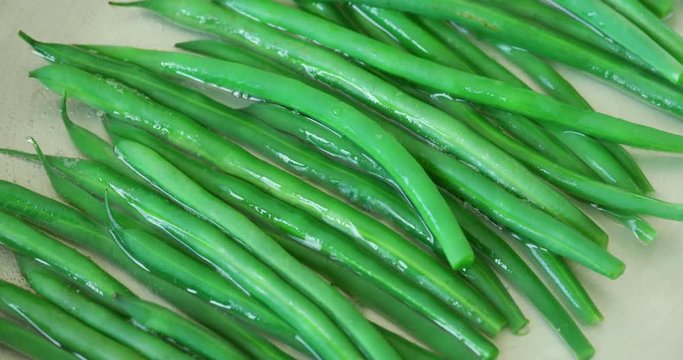 Close-up static shot of bright green beans cooking in a pan