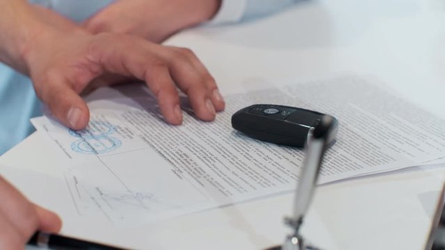 Man buying a car and signing the contract.