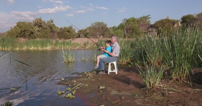 Grandfather and grandson fishing at a small lake