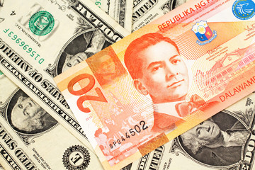 Fototapeta na wymiar An orange twenty piso bank note from the Philippines with American one dollar bills close up in macro