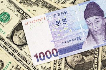A blue South Korean one thousand won bank note close up in macro on a background of American one dollar bills