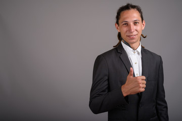 Young businessman with dreadlocks against gray background