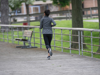 unknown female jogger runs on the boardwalk to get exercise after work