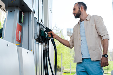 Low angle view of man holding fuel nozzle at gas station