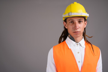 Young man construction worker against gray background