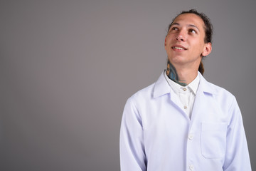 Young man doctor with dreadlocks against gray background