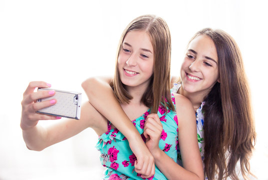 Two girls looking at smart phone, taking selfie. Social media concept