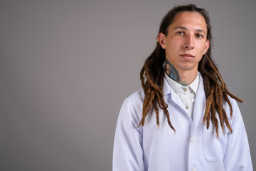 Young man doctor with dreadlocks against gray background