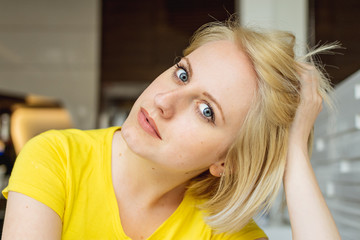 Fototapeta premium Portrait of a beautiful blonde girl with blue eyes in yellow t-shirt.