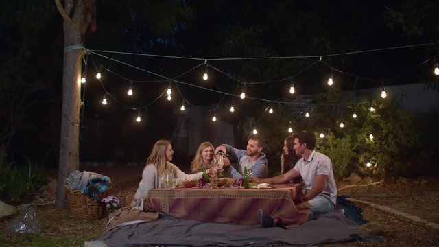 Host pouring drinks at a dinner party in garden