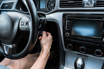 cropped view of woman putting car key in keyhole while sitting in car