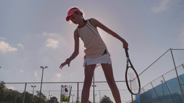Sporty young woman bouncing tennis ball before serving
