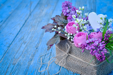 Flowers in a basket on blue wooden background. Copy space