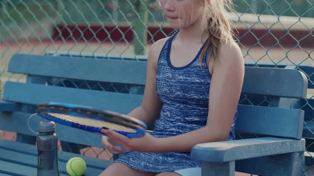 Tween girl at tennis court waiting to play