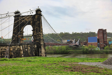 The Wheeling Suspension bridge is a historic landmark that spans the Ohio river into Wheeling , West Virginia.