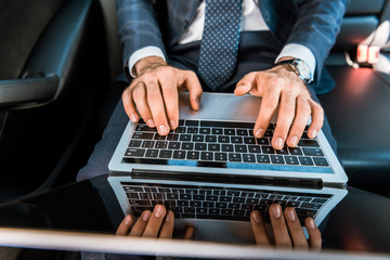 selective focus of businessman typing on laptop in car