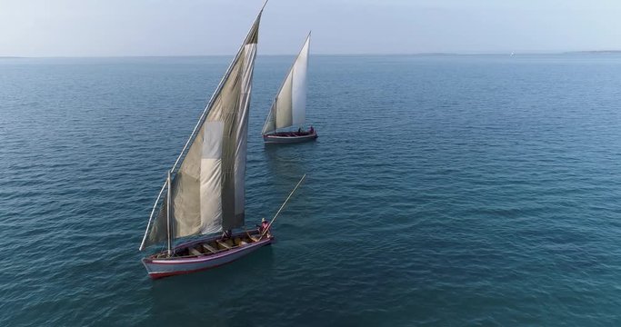 Aerial close-up view of two traditional dhow sailing boats fihsing on a beautiful scenic estuary  
