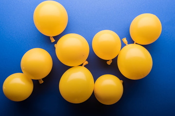 Top view of festive yellow balloons on blue background