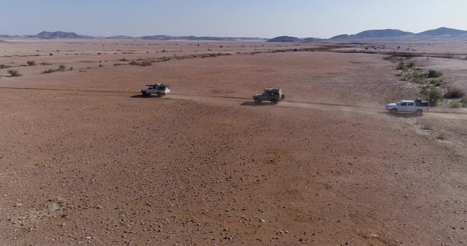 4K high aerial panning view of 4x4 vehicles driving through the Namib desert, Namibia