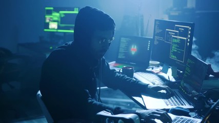 Profile of concentrated hacker breaking security system attacking the server in the dark. Close-up of man working on computer in office at night.